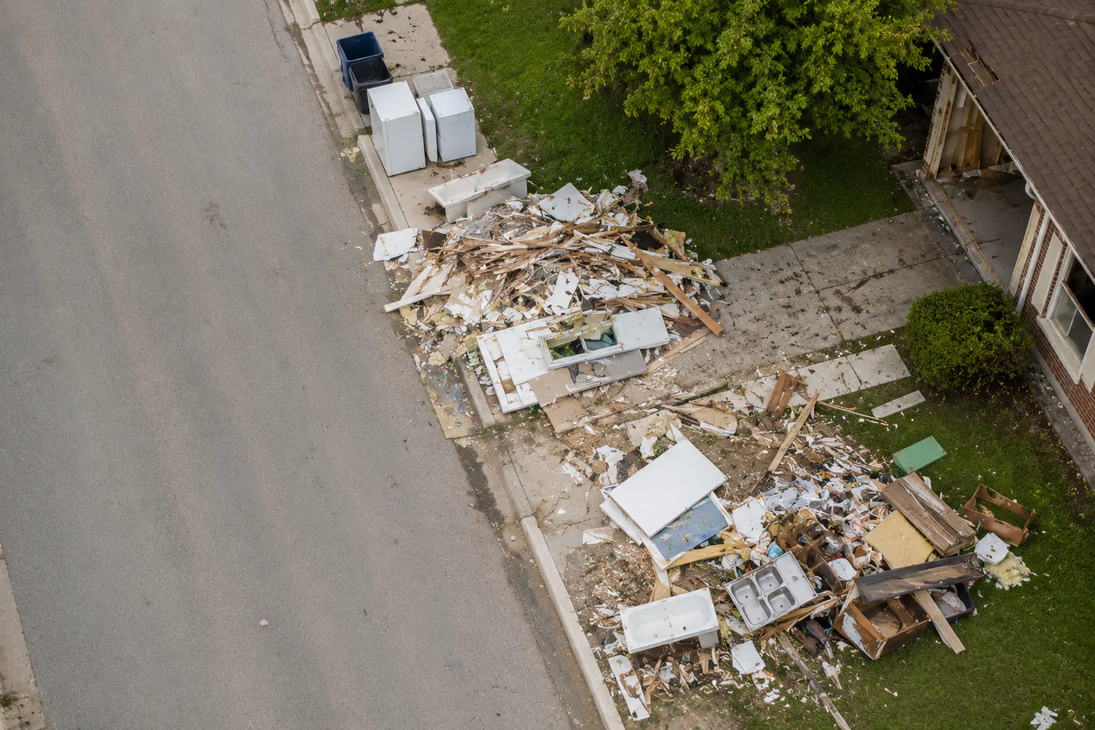 An aerial view of storm debris piled beside a residential street.