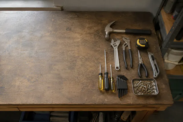 A workbench arranged with a hammer, pliers, screwdrivers, wrenches, and measuring tools.