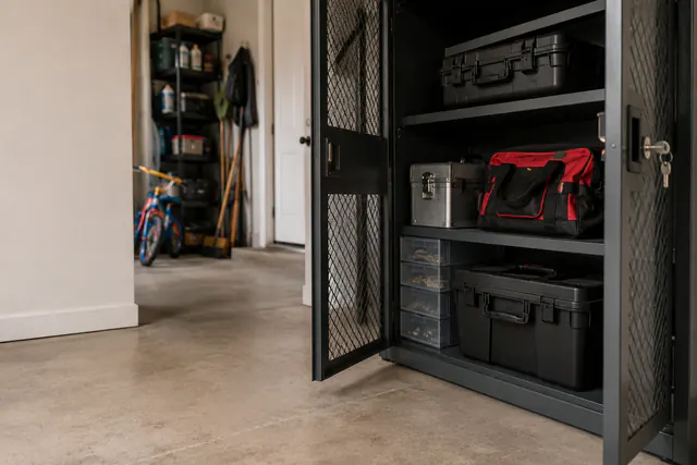 A garage storage wall with hand tools, storage bins, a secured gate, and an open exit path.